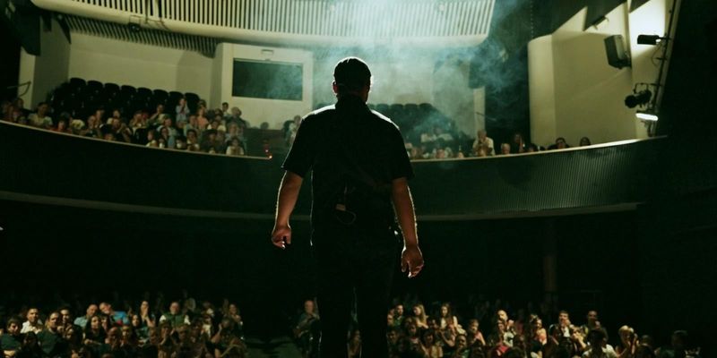 Sena de espaldas en el escenario, frente a un teatro lleno
